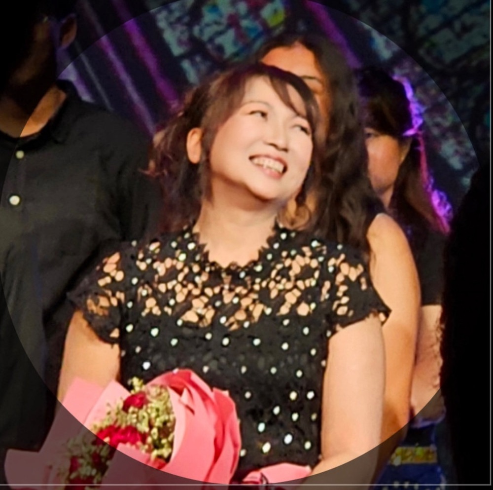 Joyce Goh smiling on stage after a concert, holding a bouquet
