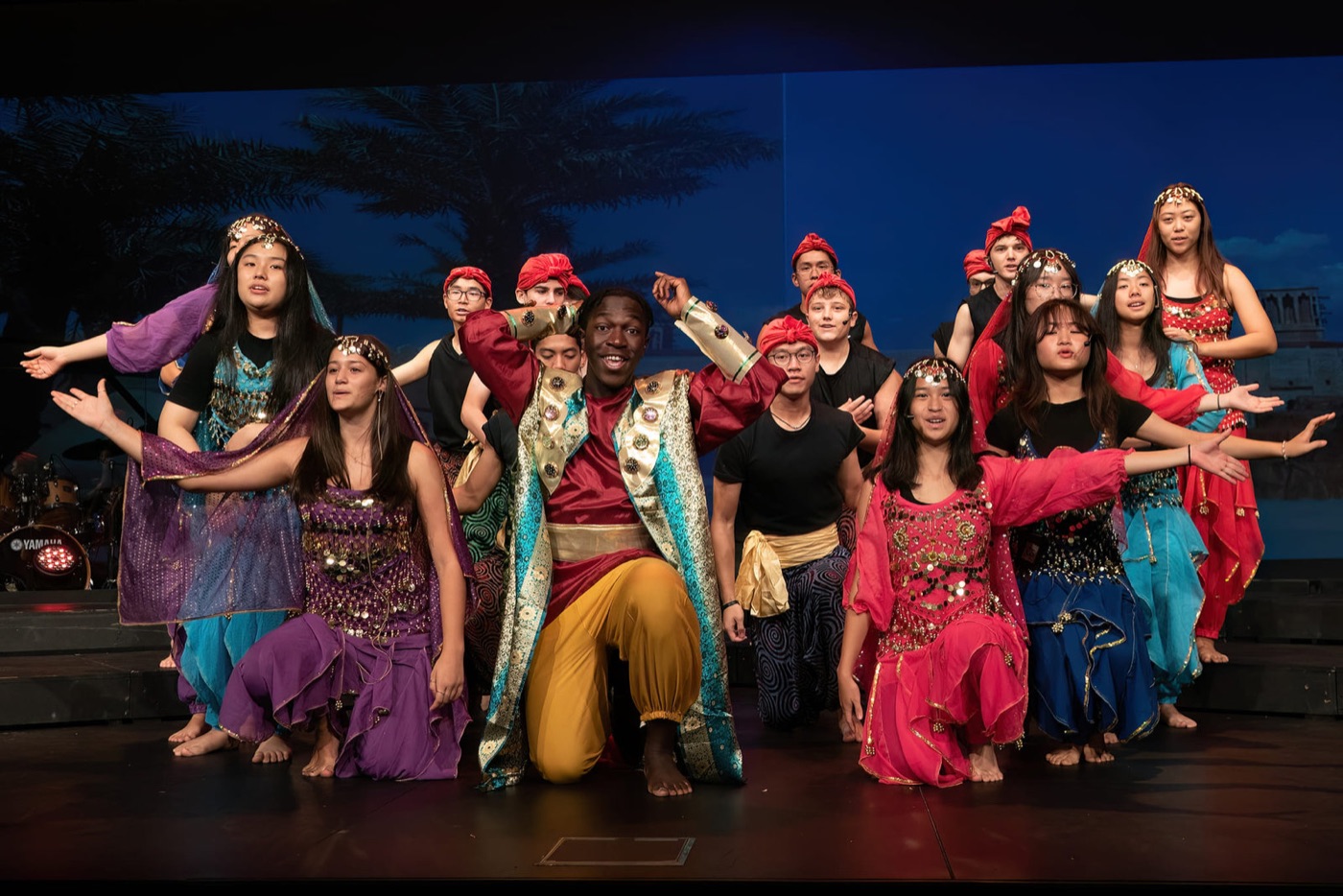The full cast of a musical posing on stage in costume